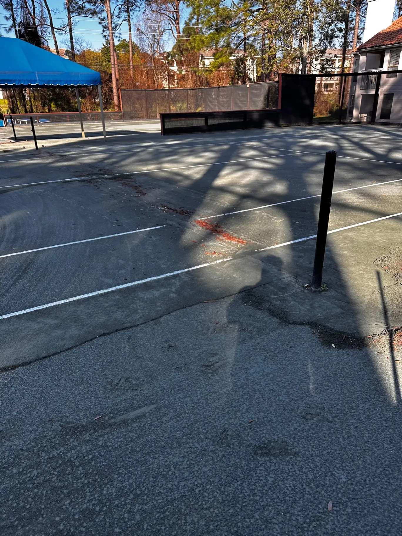 Court surface with visible uneven areas beside a net post.